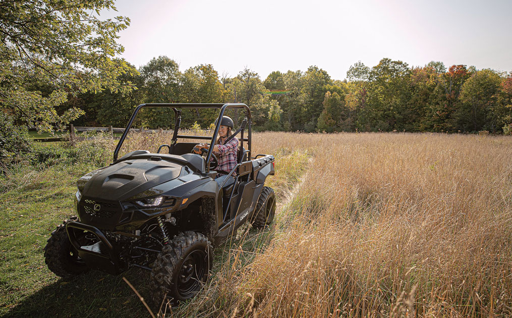 Woman drivin UTV in a field of grass
