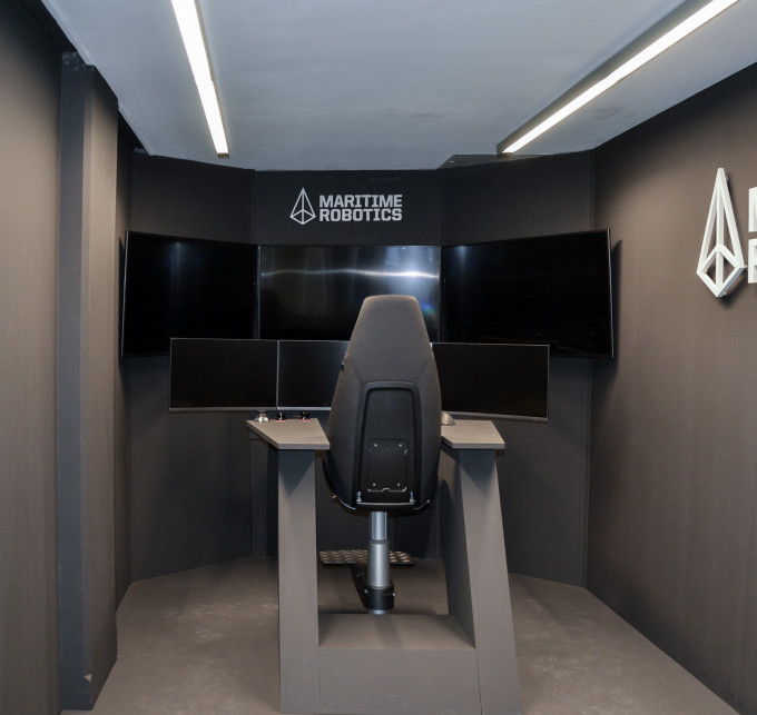 A black chair in a black room facing six screens.