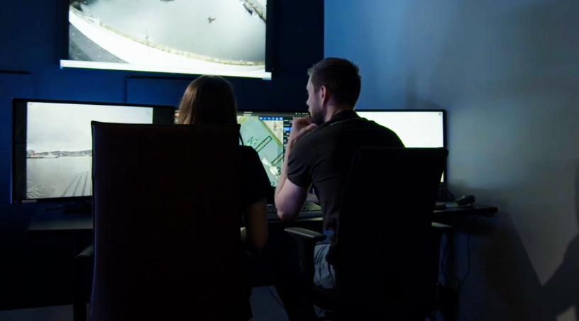 Two employees looking at screens in a VCS room.
