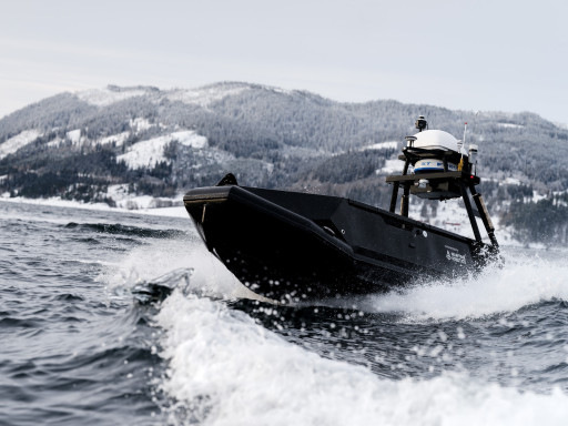 Low-angle close-up of the Mariner USV cutting through water at speed, highlighting its sharp bow and sensor mast.