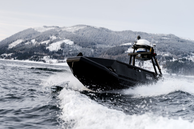 Low-angle close-up of the Mariner USV cutting through water at speed, highlighting its sharp bow and sensor mast.