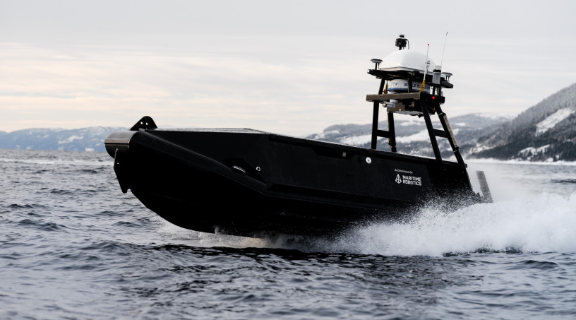 Mariner USV speeding across the ocean surface with spray.
