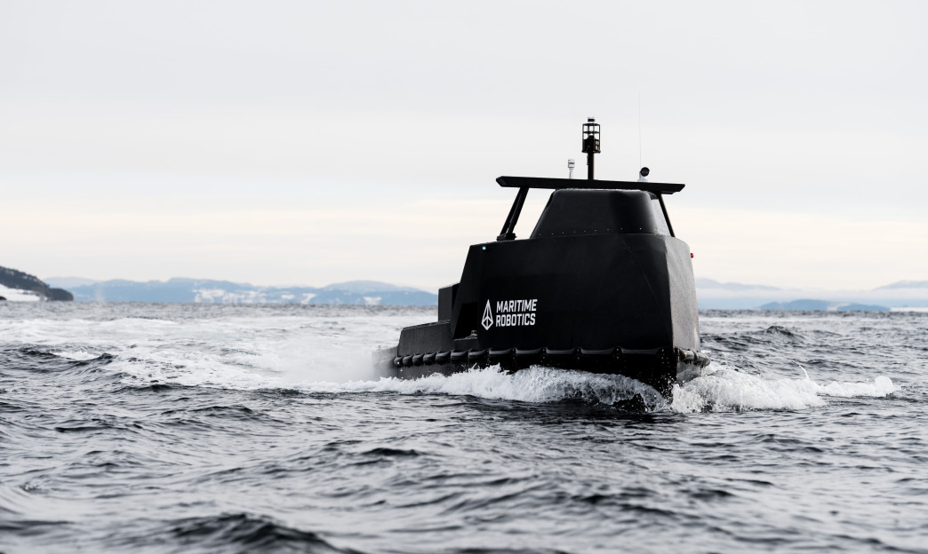 Perspective view of the Mariner X USV navigating across open water with its communication and sensor systems visible.
