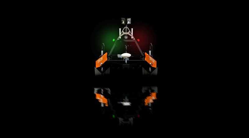 Front-facing view of the Otter USV with active green and red navigation lights and SeaSight system.
